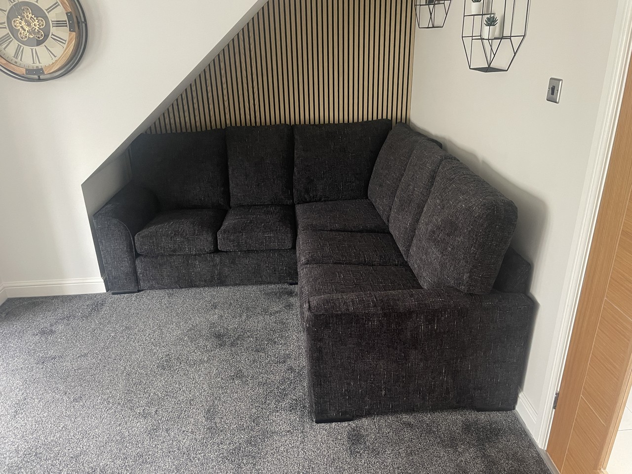 Compact corner sofa positioned beneath a staircase