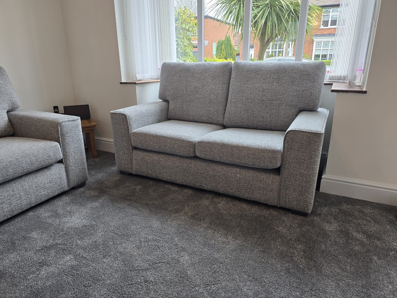 Light grey Inca sofa in a home, showing the piped arm fronts, broad cushions and low upholstered base.