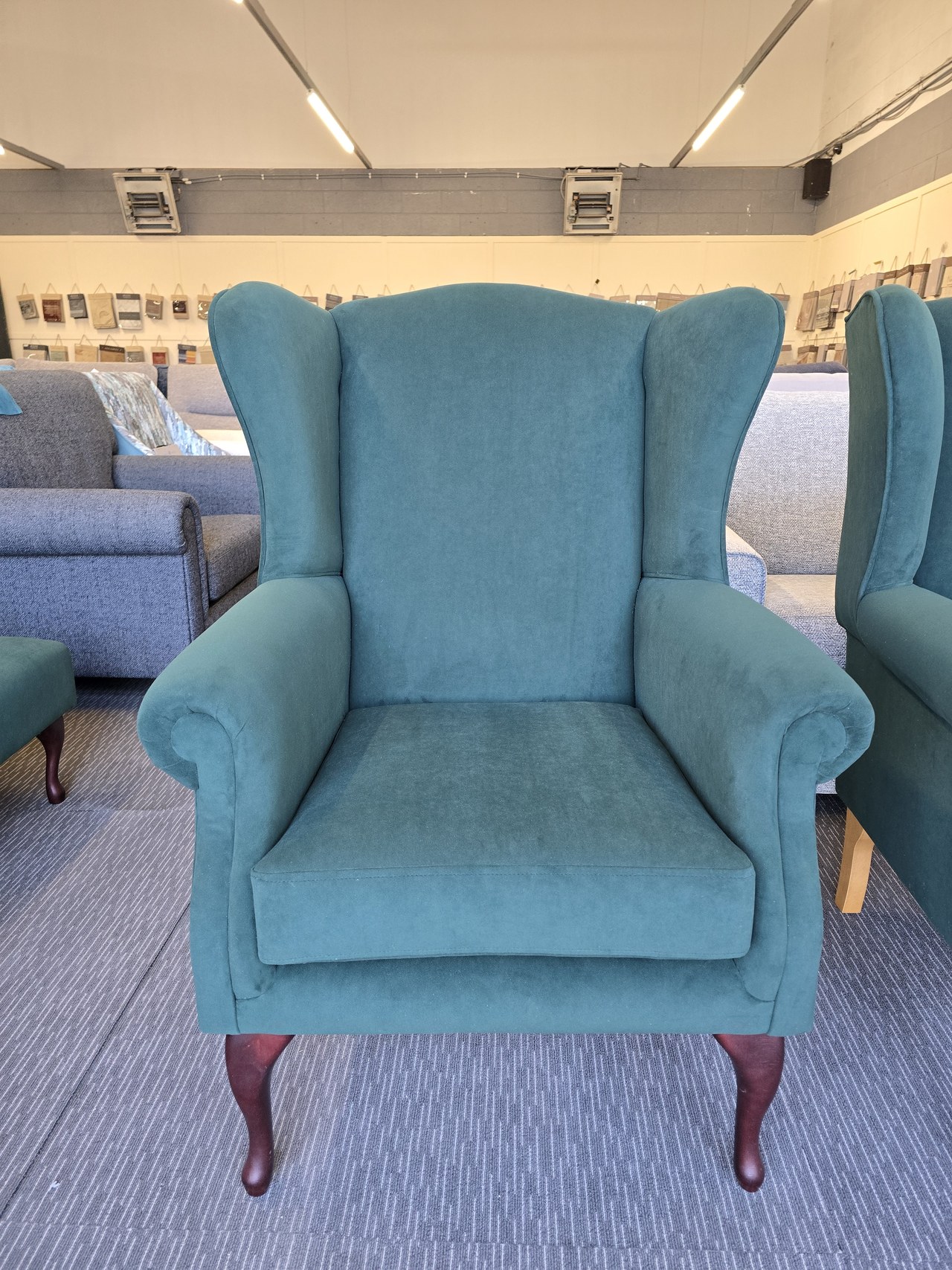 Teal Queen Anne-style wingback chair with scroll arms, a single seat cushion and curved dark front legs.
