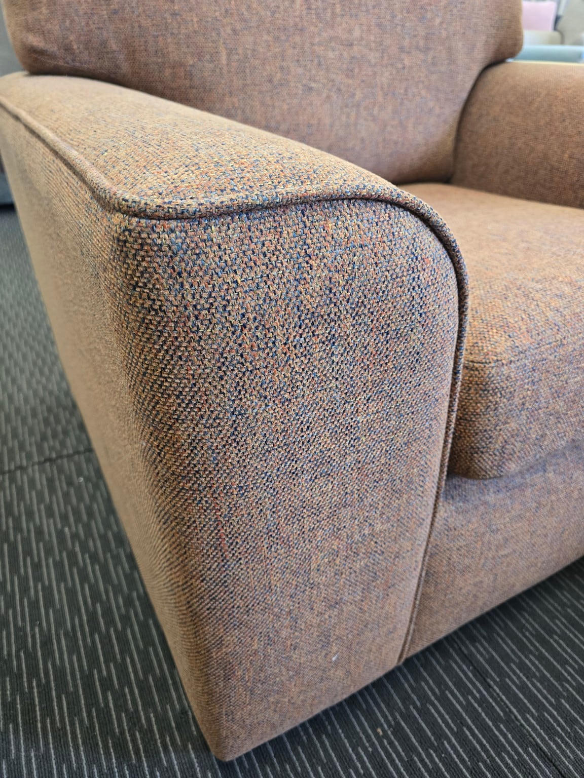Close-up of the orange Otto’s textured upholstery and piped arm