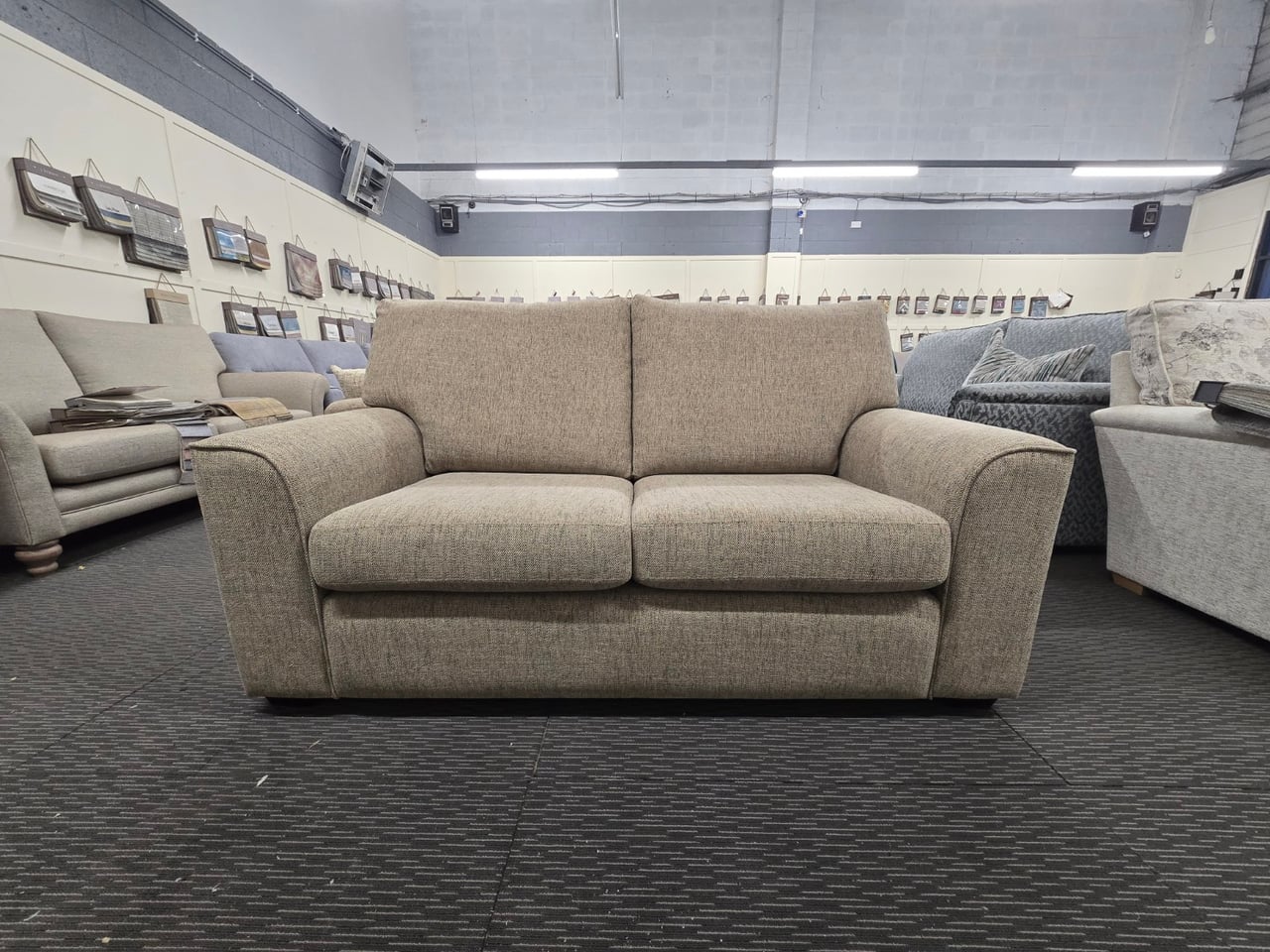 Brown Otto 2.5-seater seen from the front, with shaped piped arms and two back cushions