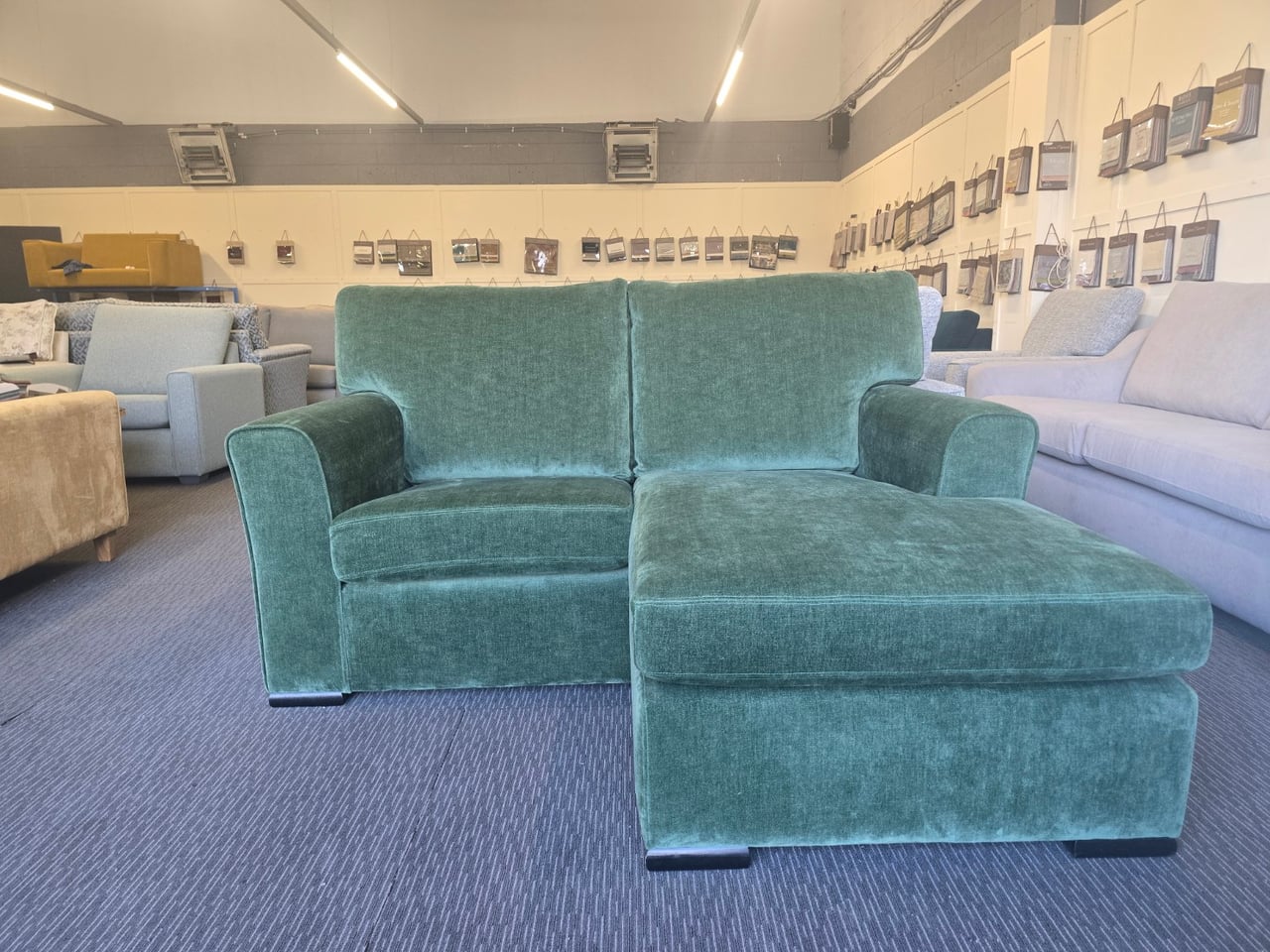Green Shelly sofa with chaise seen from the front in the showroom